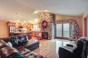 A spacious living area with a stone fireplace, a dining area, and a kitchen with wooden cabinets.