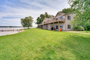 A two-story house with a covered porch, a grassy yard, and a view of a lake.
