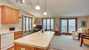 A spacious kitchen with wooden cabinets, a central island, and a view of the sea through large windows. - 519c On the Lake Hot Tub Pool Table 10 Beds (Howard Lake)