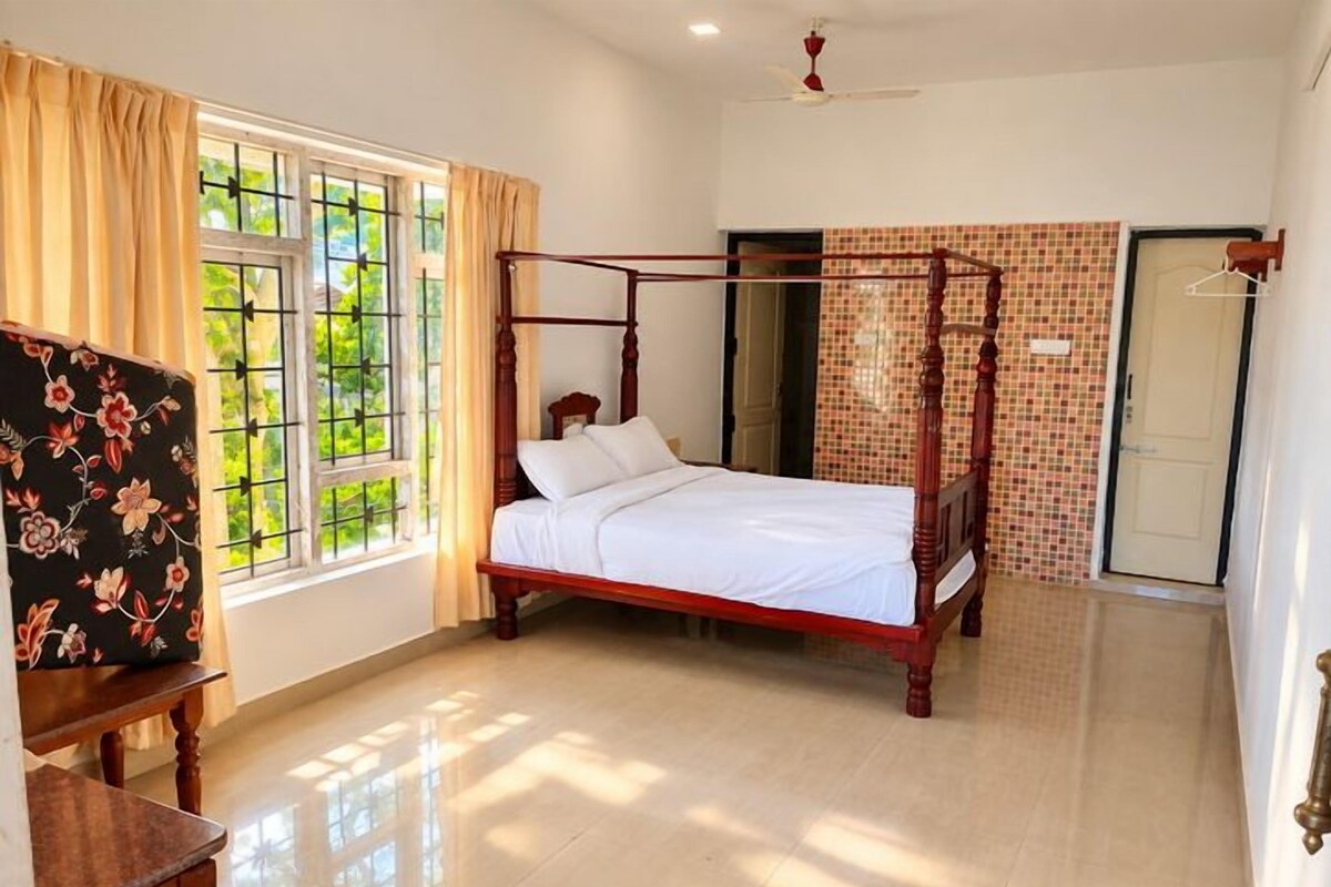 Un dormitorio con cama con dosel, una ventana con cortinas, una silla y suelo de baldosas.
