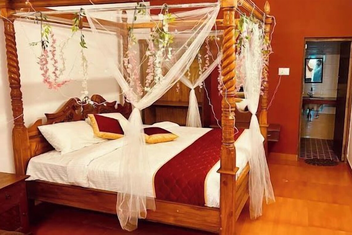 Una cama con dosel, ropa de cama blanca y detalles en rojo.