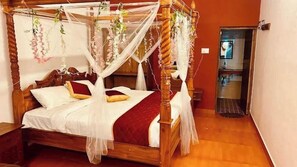 A four-poster bed with a canopy, white bedding, and red accents.