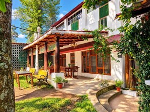 A house with a covered patio, outdoor seating, and potted plants.