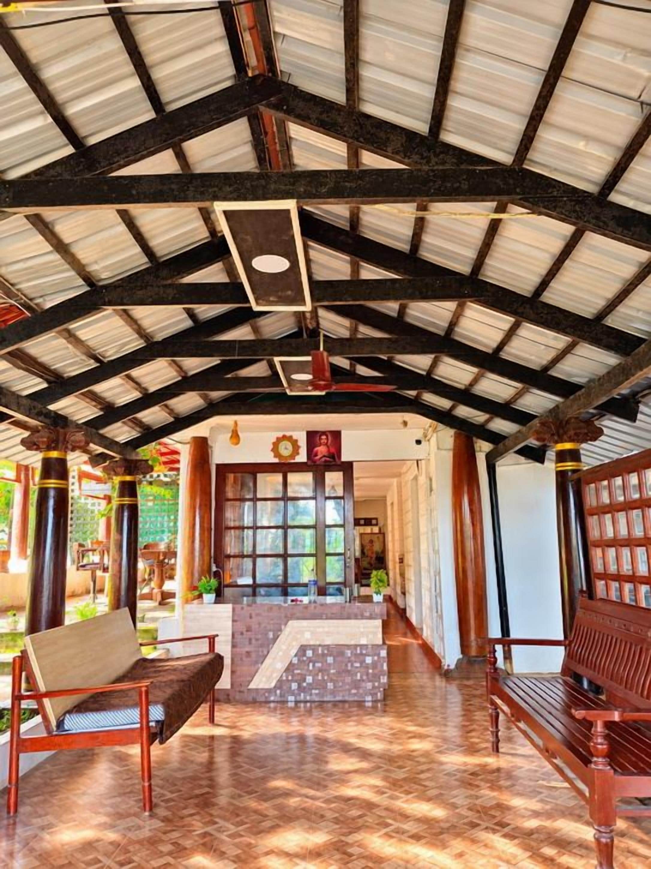 An interior with a high ceiling, a central staircase, and seating areas.