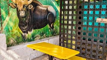 A covered outdoor area with a yellow table and benches, a mural of a bull, and a no-smoking sign.