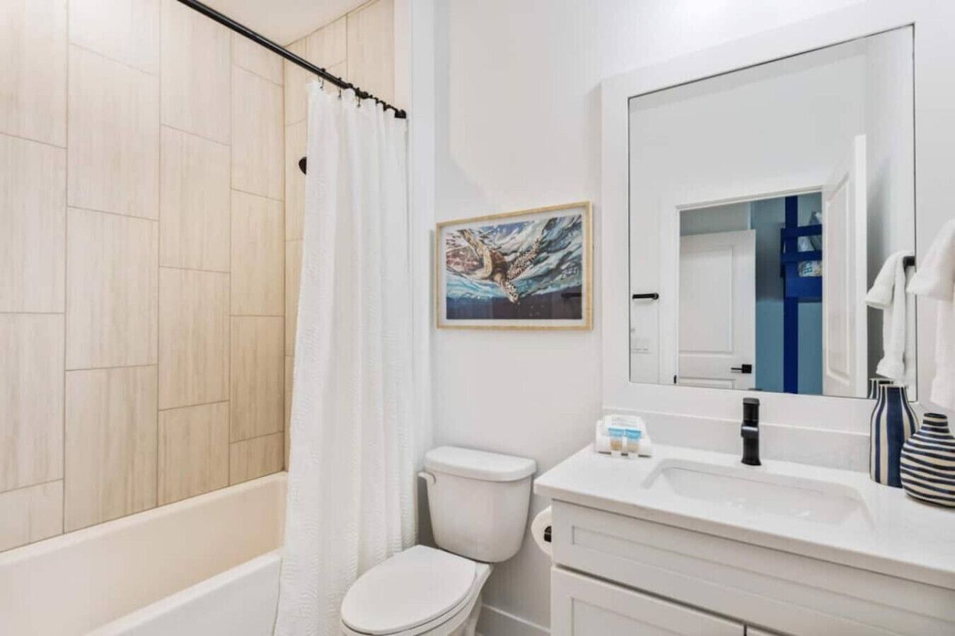 Ein Badezimmer mit Dusche, Toilette, Waschbecken und einem gerahmten Bild an der Wand.