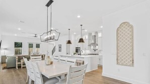A modern kitchen with white cabinetry, a central island, pendant lighting, and a large window. - 543 Private Pool Beach Golf Cart 12 Bedroom (Santa Rosa Beach)