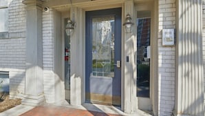 A building entrance with a blue door, numbered 110, and two wall-mounted lanterns. - Apex Executive Apartments - 30th Ave (Nashville)