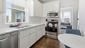 A modern kitchen with white cabinets, a Bosch dishwasher, a microwave, and an oven. - Apex Executive Apartments - 30th Ave (Nashville)