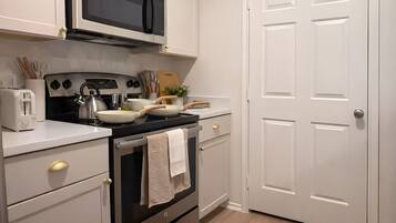 Une cuisine équipée d’un four à micro-ondes, d’une cuisinière, d’un four et de meubles blancs.