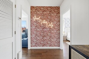 A hallway with a brick wall and a neon sign that reads "Good Vibes Only". - Central 3BR Apt Minutes to Downtown Parking (Nashville)