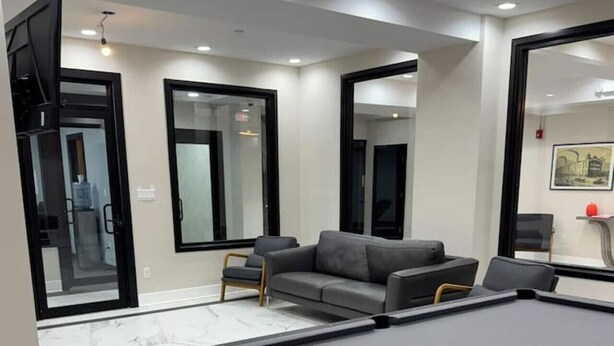 A modern room with a pool table, a grey sofa, and a large mirror.