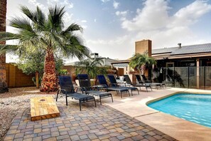 Un espace piscine avec des chaises longues, un palmier et une terrasse en briques.