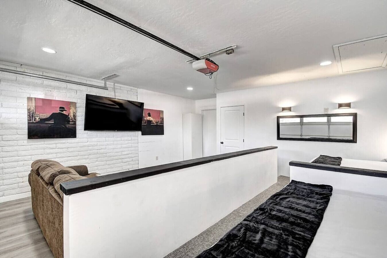 A modern hotel lobby with a reception desk, a sofa, a black rug, and artwork on the walls.