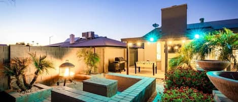A patio area with a barbecue grill, outdoor seating, and potted plants.