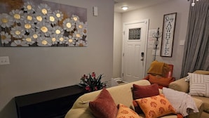Un salón con un sofá color beige, un banco negro y una obra de arte colgada en la pared.