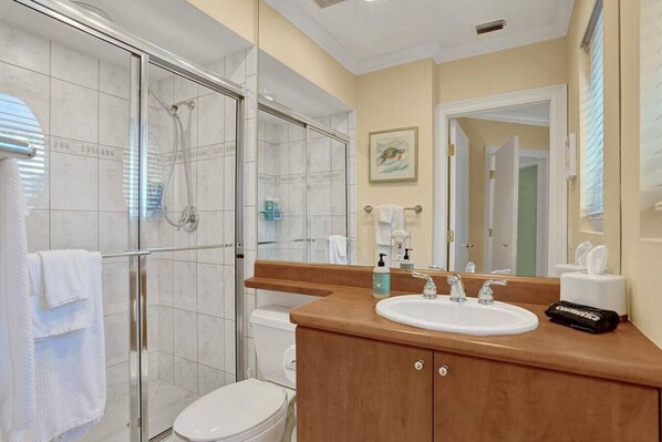 A modern bathroom with a glass-enclosed shower, a wooden vanity with a sink, and a toilet.