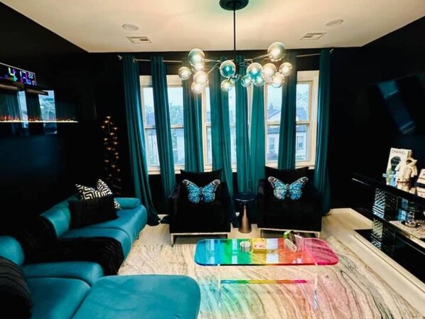 A modern living room with a sofa, chairs, a coffee table, and a chandelier.