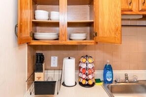 A kitchen with wooden cabinets, a dish rack, a knife block, a paper towel holder, and a dish soap bottle. - 610b Large One Bedroom Downtown! (Albany)