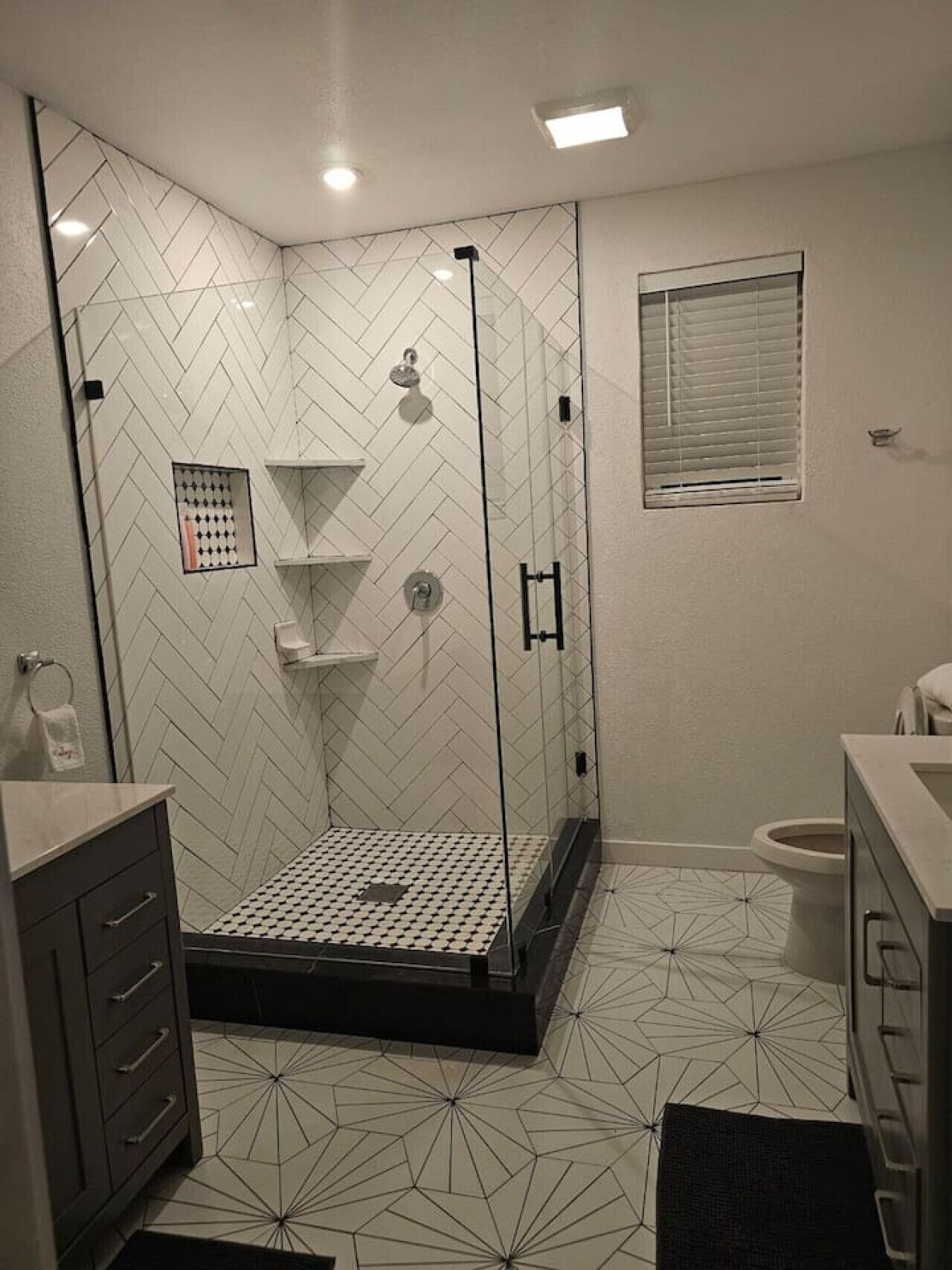 A modern bathroom with a glass-enclosed shower, a toilet, and a sink.