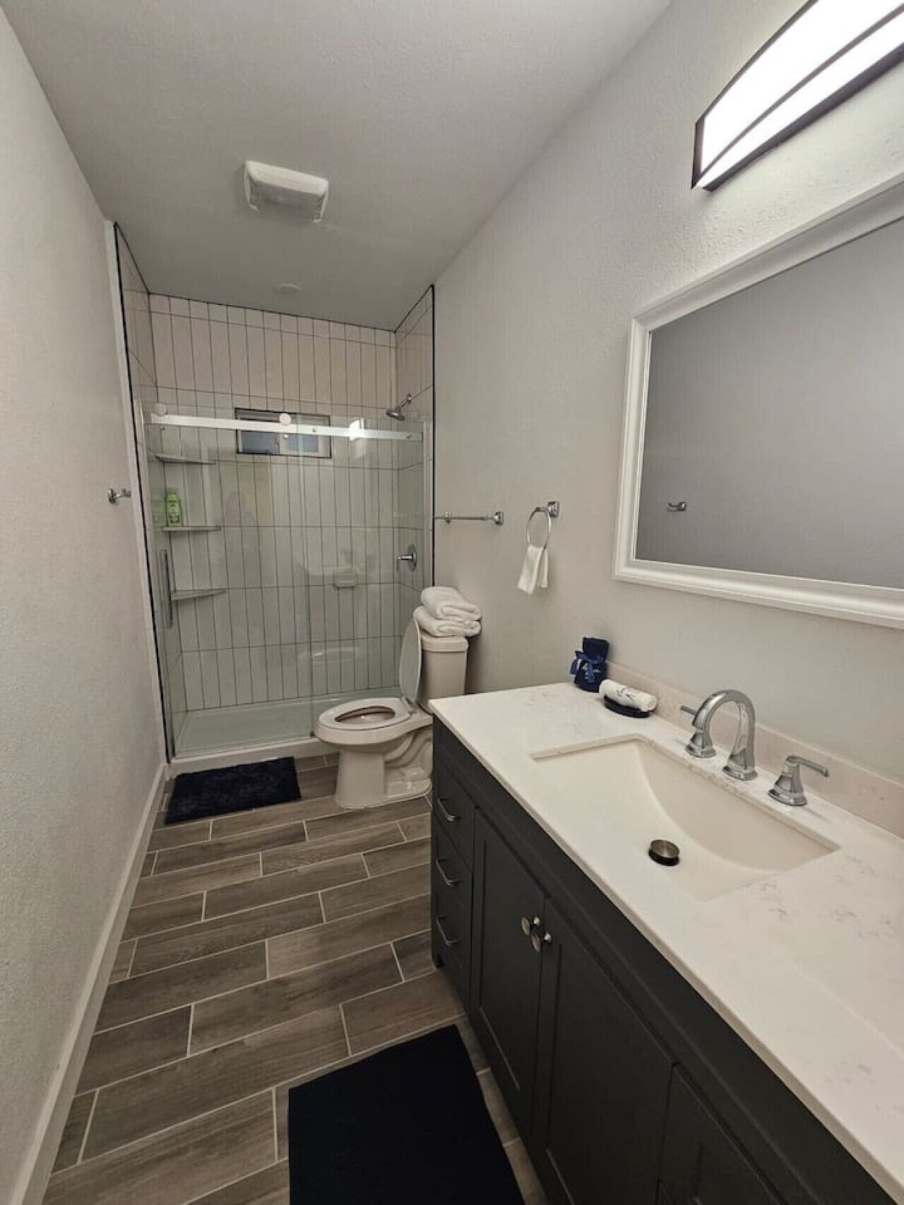 A modern bathroom with a shower, toilet, and sink.