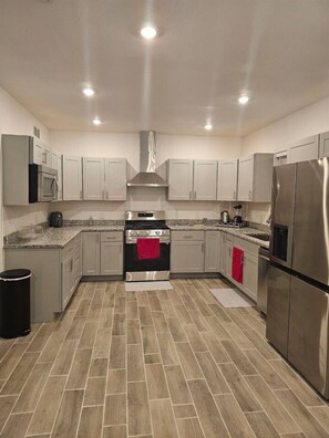 Una cocina moderna con electrodomésticos de acero inoxidable, armarios de gris claro y un patrón de suelo tipo espiga.