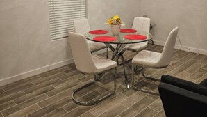 A dining area with a glass table, four white chairs, and a vase with yellow flowers. - 632 4 Large Bedrooms Spacious Private Yard (Dallas)