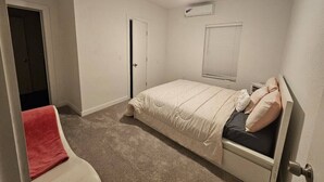 A bedroom with a single bed, a ceiling fan, an air conditioning unit, and a door leading to another room. - 632 4 Large Bedrooms Spacious Private Yard (Dallas)