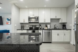 A modern kitchen with white cabinets, stainless steel appliances, and a marble countertop. - 561j Large 2 Bedroom With King bed and Patio! (Orlando)
