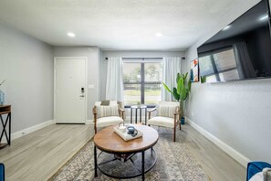 A room with a round table, two chairs, a door, and a window with curtains. - 561j Large 2 Bedroom With King bed and Patio! (Orlando)