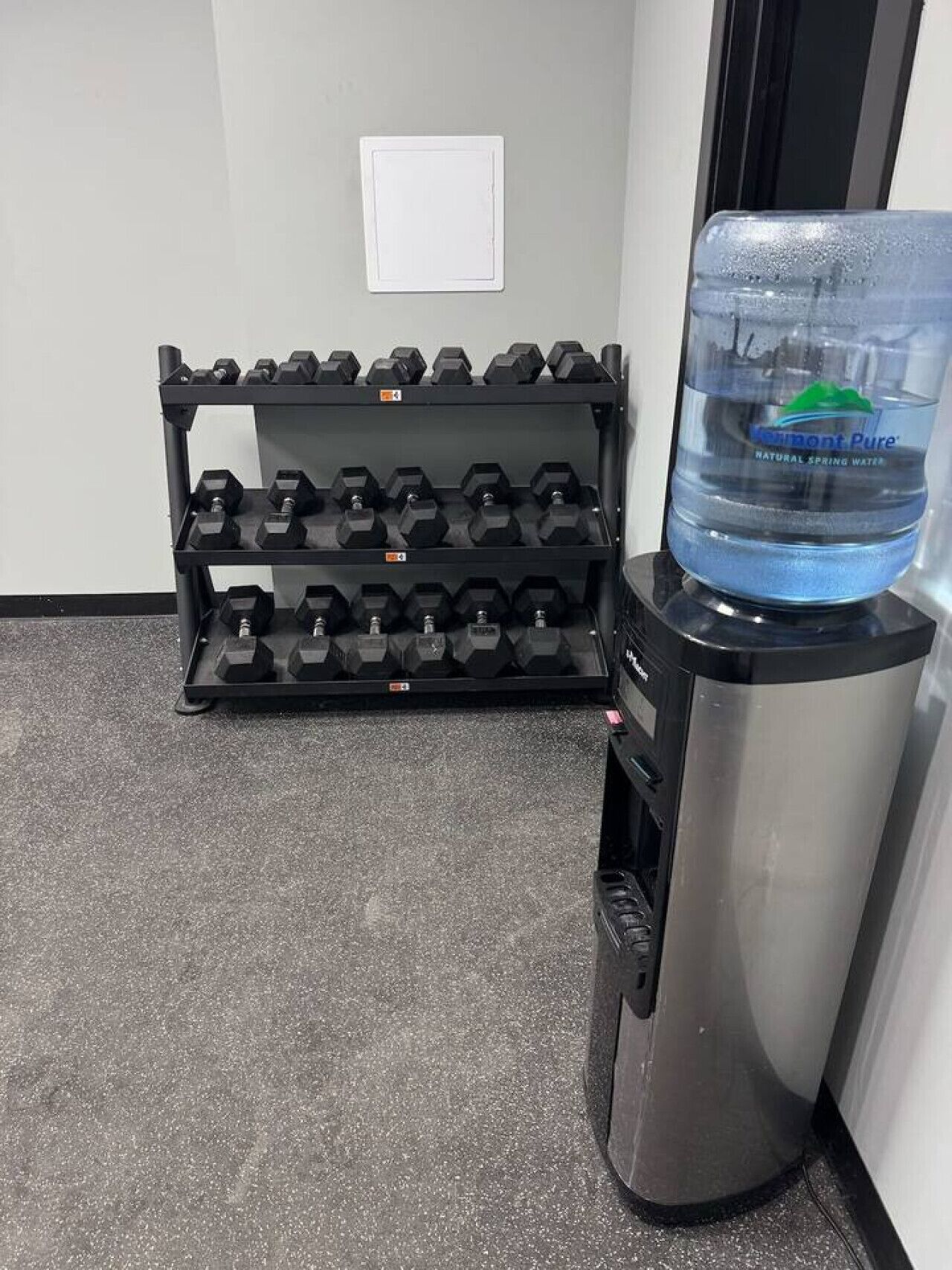 Ein Wasserspender mit einer Wasserflasche und einem Rack an Hanteln.