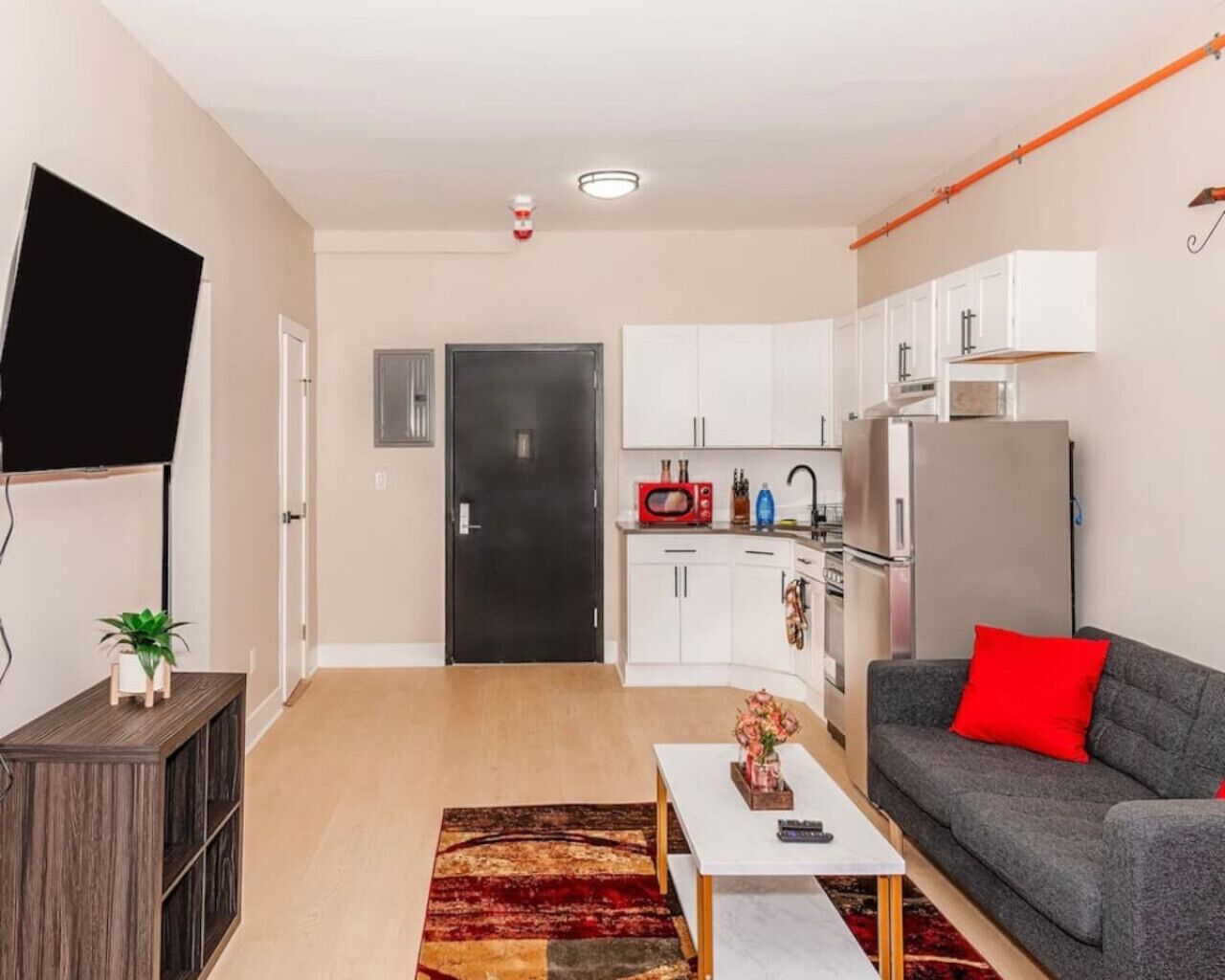 A modern apartment with a living room, kitchen, and a TV mounted on the wall.