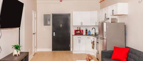 A modern apartment with a living room, kitchen, and a TV mounted on the wall.