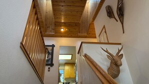 A wooden staircase with a ceiling light, a wall-mounted deer head decoration, and a kitchen visible in the background. - 620 Large 3 Bedrooms Outdoor Seating (Kings Beach)