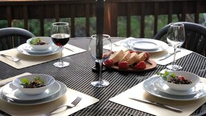 A dining table set for four with white plates, bowls, and cutlery, and glasses of red wine. - 620 Large 3 Bedrooms Outdoor Seating (Kings Beach)