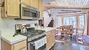 A kitchen with wooden cabinets, a stove, and a microwave. There is a dining area with chairs and a table. - 620 Large 3 Bedrooms Outdoor Seating (Kings Beach)