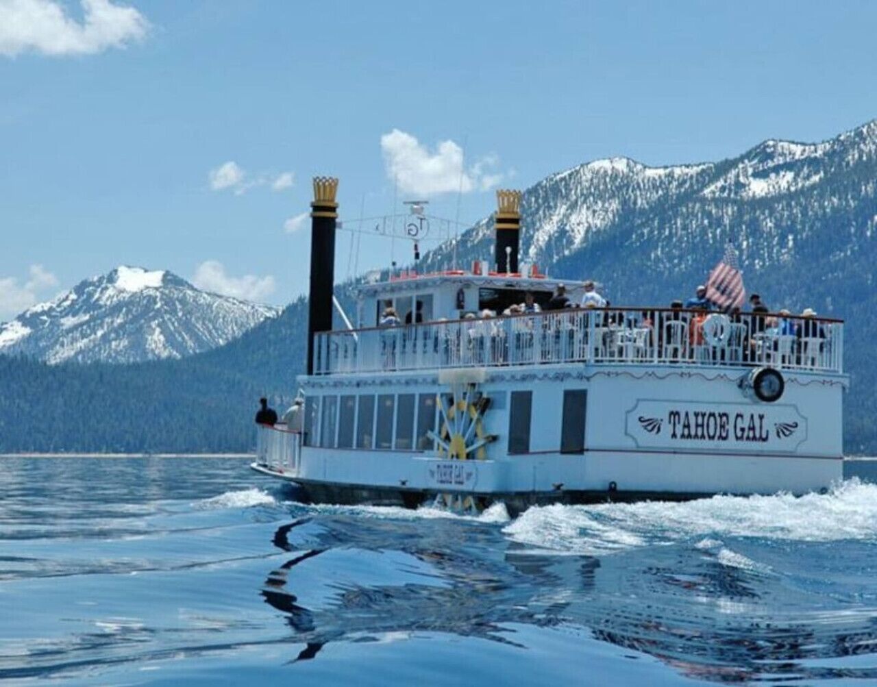 Un bateau appelé Tahoe Gal, doté d’un pont, accueillant des passagers, et avec une chaîne de montagnes en toile de fond.