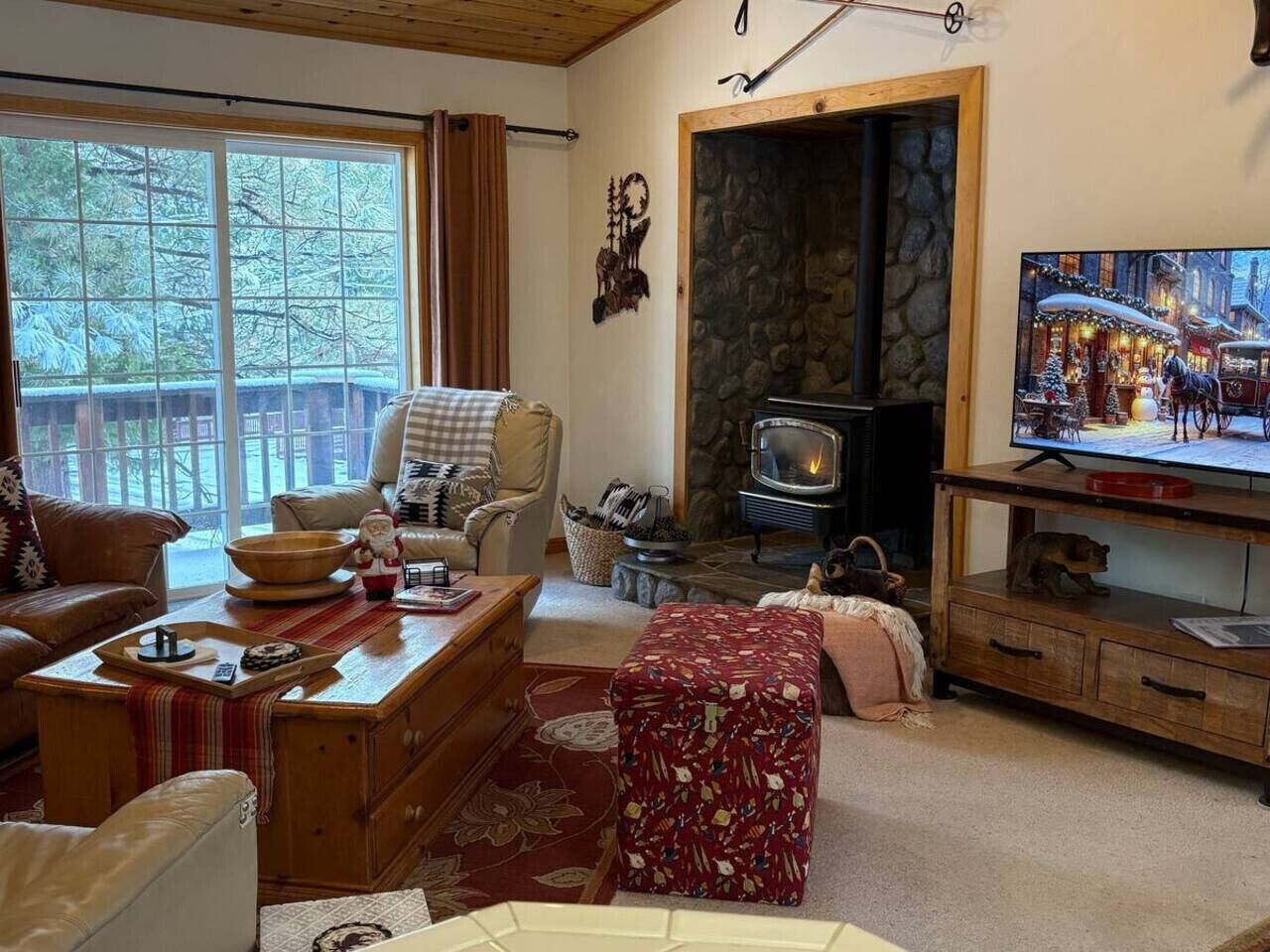 A cozy living room with a fireplace, a television, and a large window.