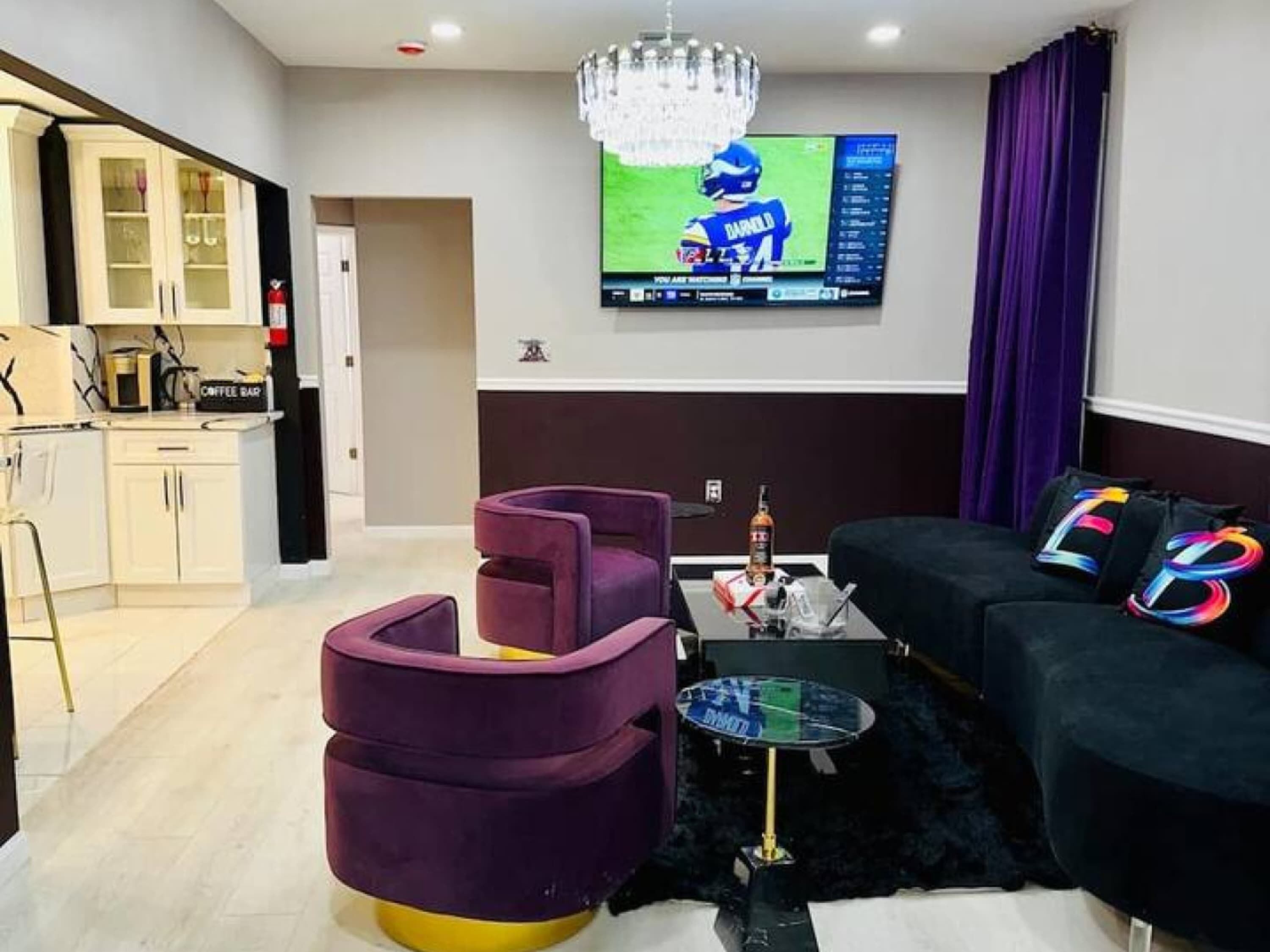 A modern living room with a TV, purple armchairs, a sofa, and a coffee table.