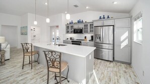 A modern kitchen with a large island, stainless steel appliances, and pendant lighting. - 561g Massive Newly Built 3 Bedroom! (Wildwood)