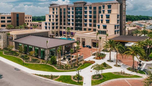 A multi-story hotel with a central courtyard, outdoor seating, and a swimming pool. - 561g Massive Newly Built 3 Bedroom! (Wildwood)