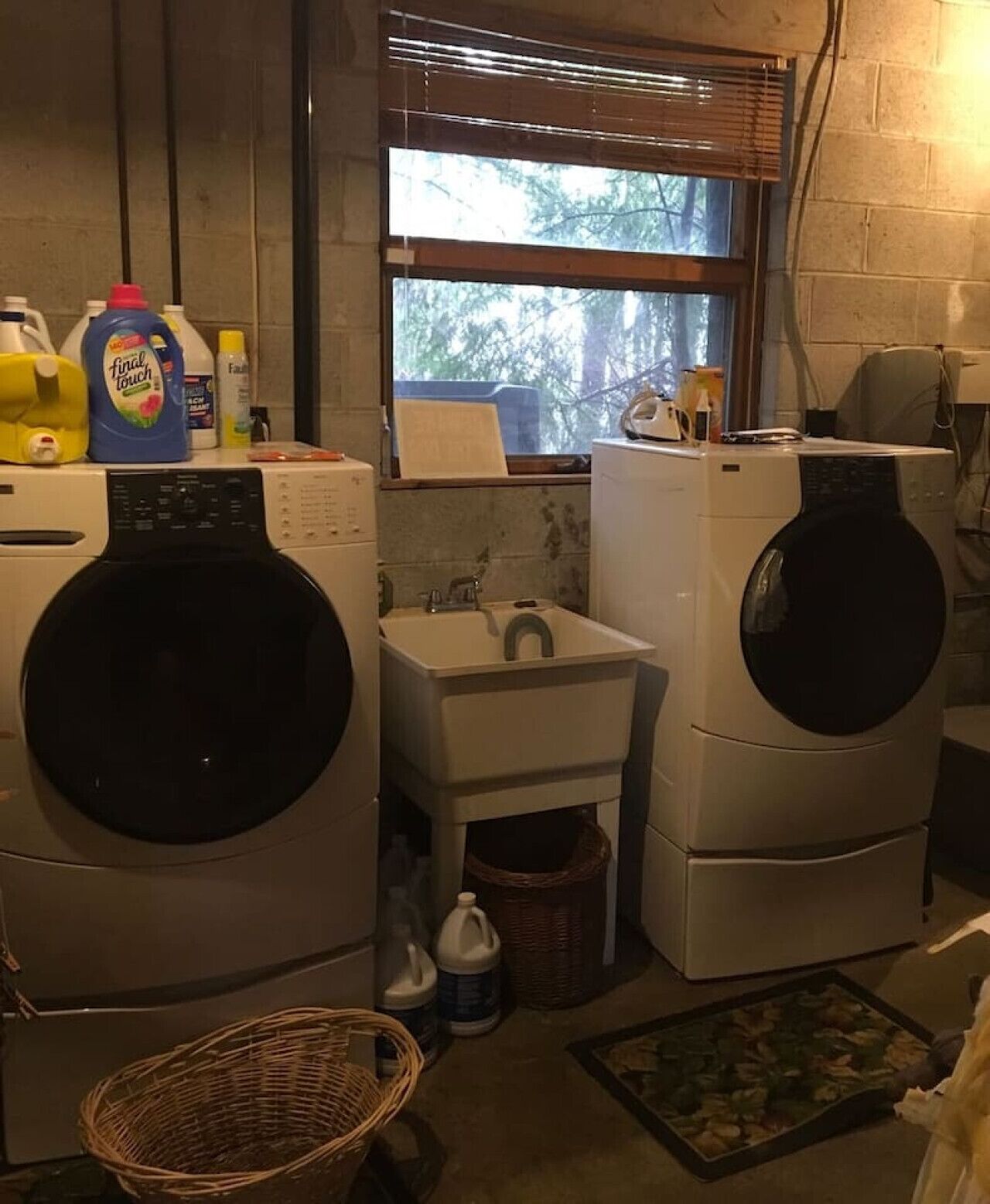 A laundry room with two front-loading washers, a sink, and a window.