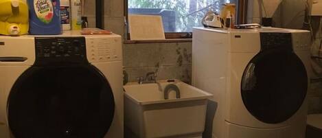 A laundry room with two front-loading washers, a sink, and a window.