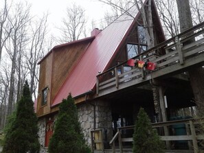 A rustic cabin with a stone exterior and a red metal roof, featuring a wooden staircase leading to a deck. - 653 4 Bedrooms Fireplace Pool Table Peaceful (Champion)