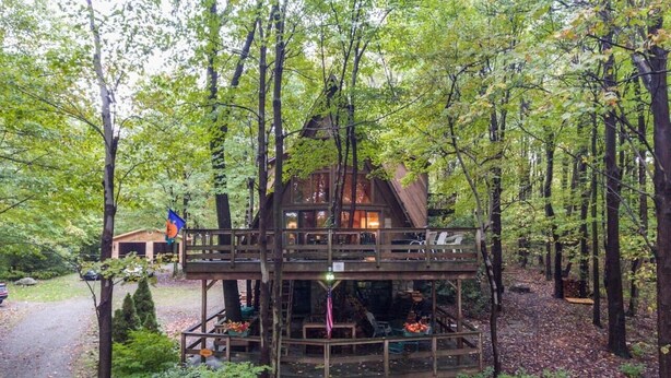 Eine Hütte im Wald mit einer Holzterrasse und einer kleinen Veranda.