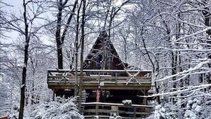 Eine Holzhütte, umgeben von schneebedeckten Bäumen.