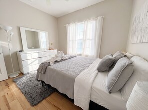 A bedroom with a bed, a dresser, a mirror, and a window with curtains. - Escape Heaven! Tranquility Guaranteed, Fully Fenced Pet Friendly (Palm Coast)