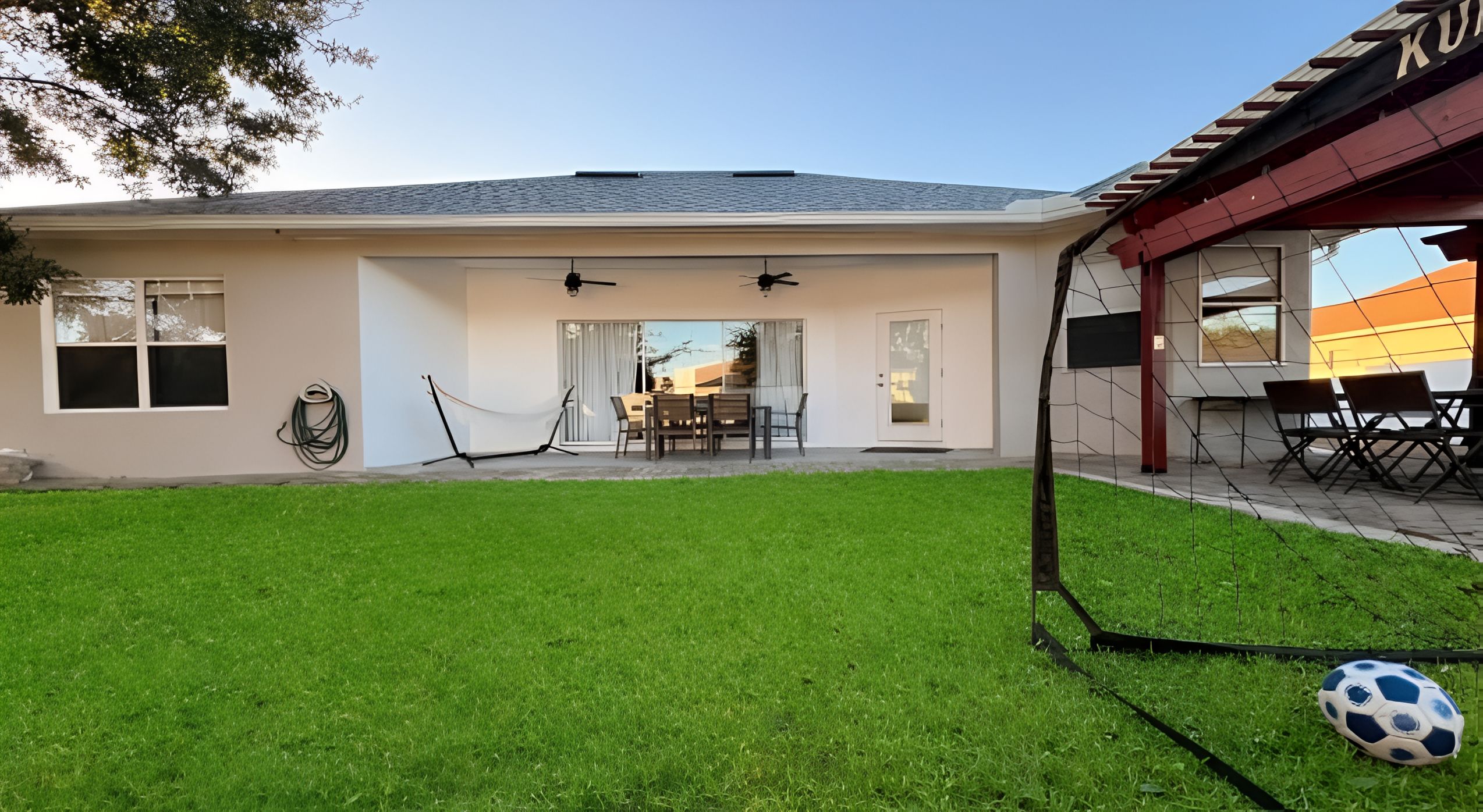 Ein Haus mit Terrasse, Essbereich und überdachter Sitzgelegenheit.
