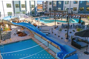 A pool area with a water slide, multiple pools, lounge chairs, and outdoor seating. - 485 Rooftop Hot Tub - Sleeps 24 (Hurricane)