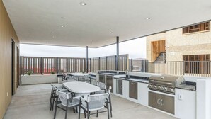 A modern outdoor kitchen with a grill, dining table, and chairs. - 485 Rooftop Hot Tub - Sleeps 24 (Hurricane)